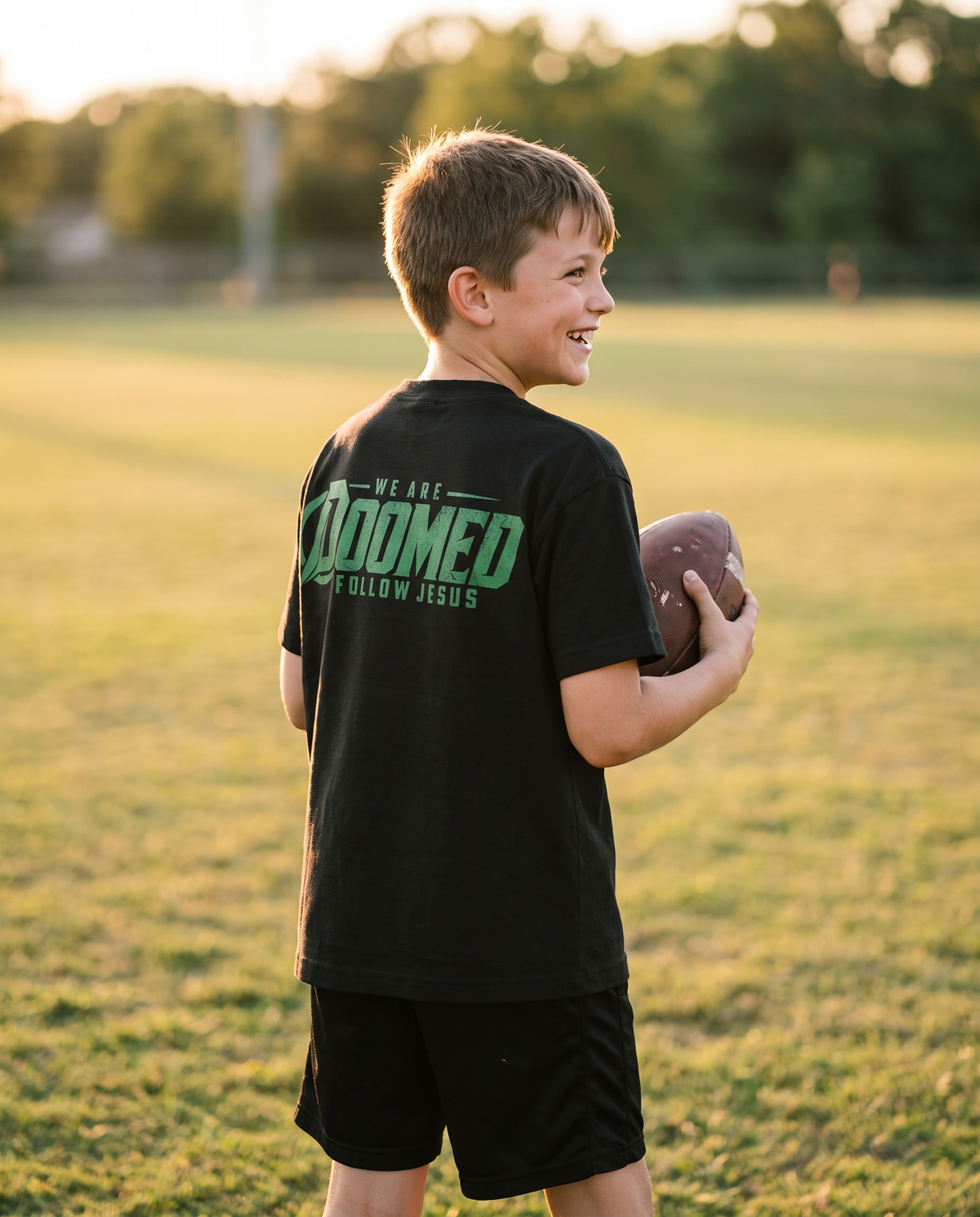 Boy in the Youth DOOMED tee holding a football