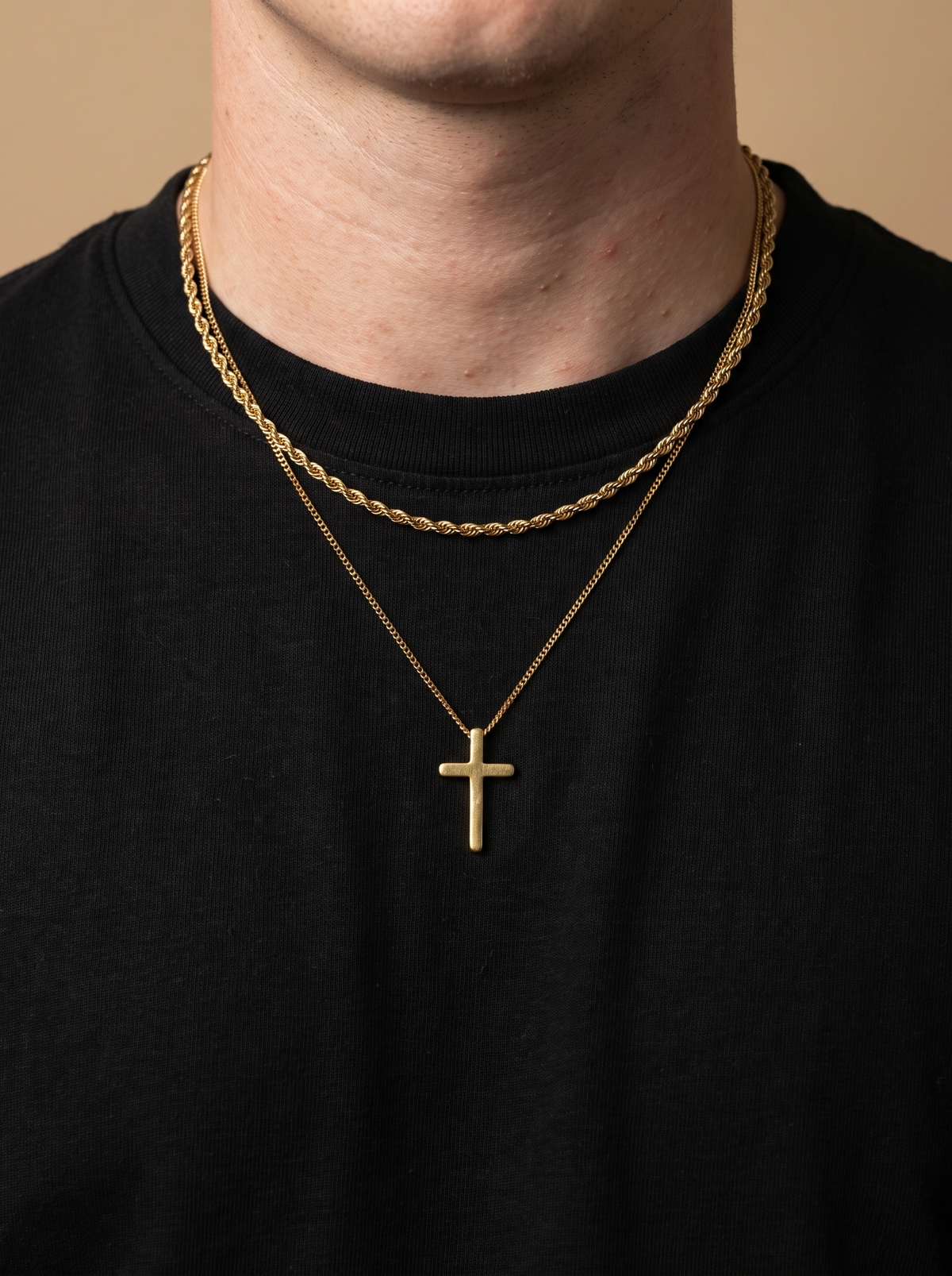 Gold cross necklace and rope chain worn over a black t-shirt