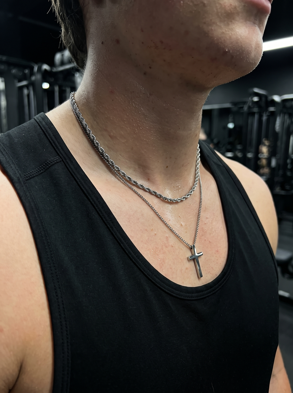 Silver cross necklace and rope chain worn in the gym
